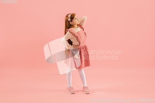 Image of Childhood and dream about big and famous future. Pretty longhair girl isolated on coral pink background