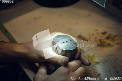 Image of Close up hands of jeweller, goldsmiths making of golden ring with gemstone using professional tools.