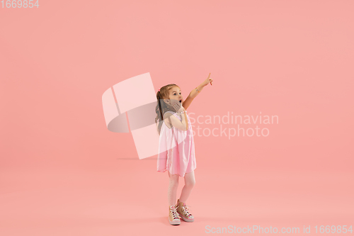 Image of Childhood and dream about big and famous future. Pretty longhair girl isolated on coral pink background