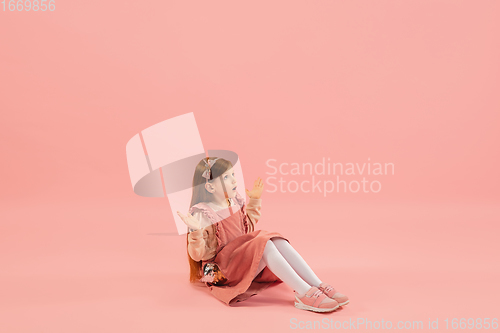 Image of Childhood and dream about big and famous future. Pretty longhair girl isolated on coral pink background