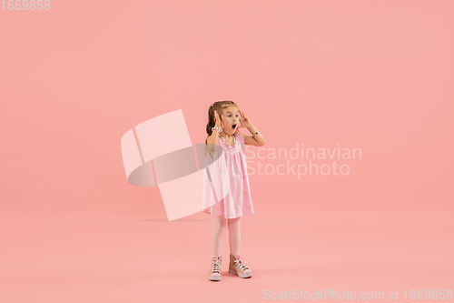 Image of Childhood and dream about big and famous future. Pretty longhair girl isolated on coral pink background