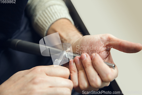 Image of Close up hands of jeweller, goldsmiths making of golden ring with gemstone using professional tools.