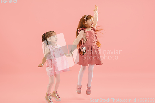 Image of Childhood and dream about big and famous future. Pretty little girls isolated on coral pink background