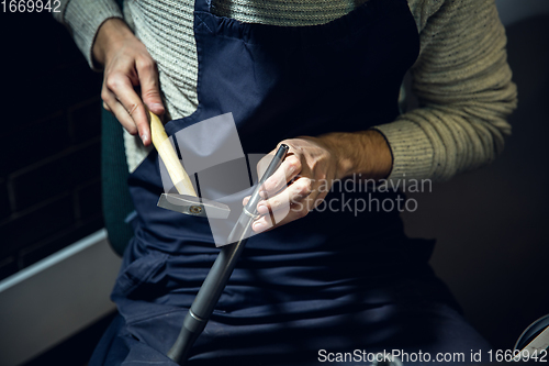 Image of Close up hands of jeweller, goldsmiths making of silver ring with gemstone using professional tools.