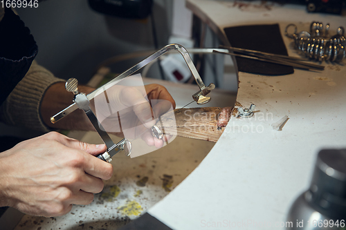 Image of Close up hands of jeweller, goldsmiths making of silver ring with gemstone using professional tools.