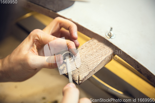 Image of Close up hands of jeweller, goldsmiths making of silver ring with gemstone using professional tools.