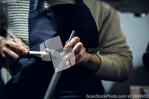 Image of Close up hands of jeweller, goldsmiths making of silver ring with gemstone using professional tools.