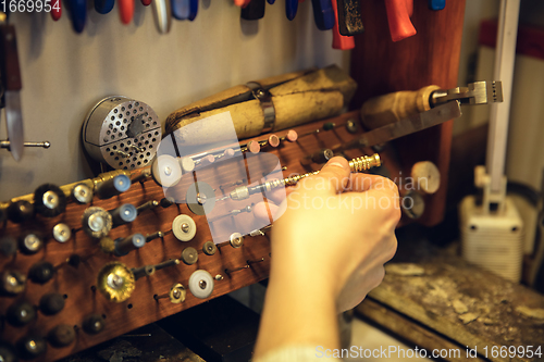 Image of Close up hands of jeweller, goldsmiths making of silver ring with gemstone using professional tools.