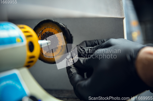 Image of Close up hands of jeweller, goldsmiths making of silver ring with gemstone using professional tools.