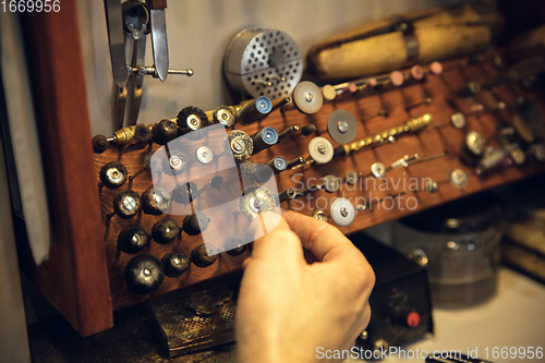 Image of Close up hands of jeweller, goldsmiths making of silver ring with gemstone using professional tools.