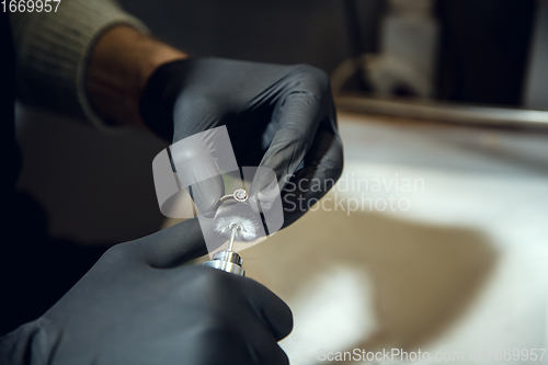 Image of Close up hands of jeweller, goldsmiths making of silver ring with gemstone using professional tools.