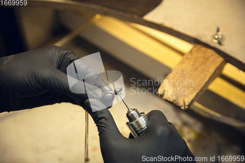 Image of Close up hands of jeweller, goldsmiths making of silver ring with gemstone using professional tools.