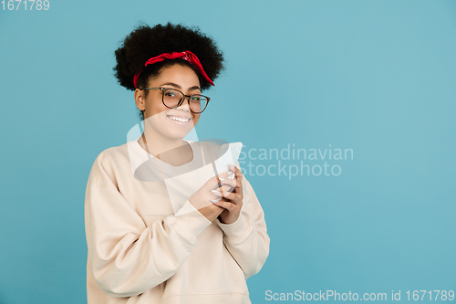 Image of African-american woman\'s portrait isolated on blue studio background with copyspace