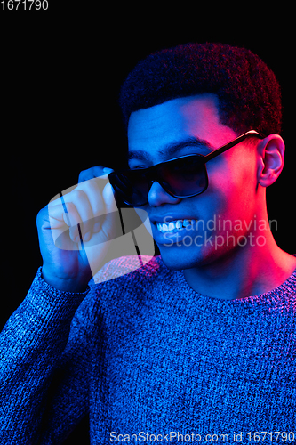 Image of African-american man\'s portrait isolated on black studio background in multicolored neon light