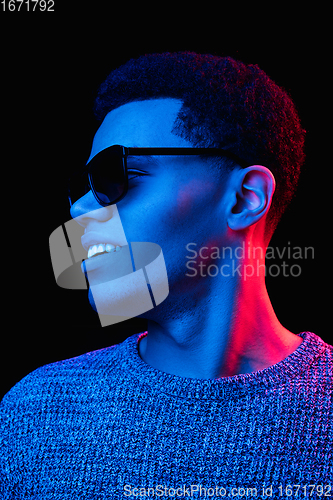 Image of African-american man\'s portrait isolated on black studio background in multicolored neon light