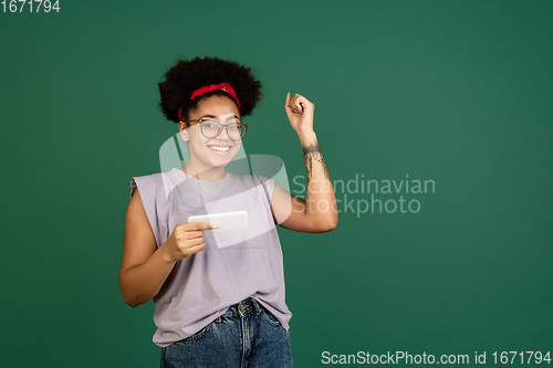 Image of African-american woman\'s portrait isolated on green studio background with copyspace