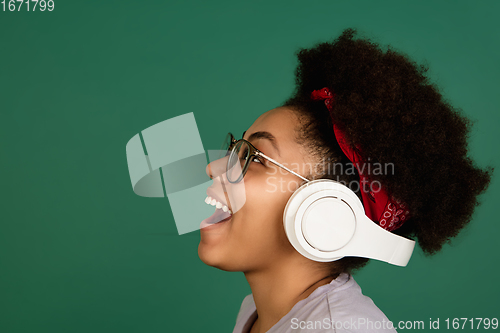 Image of African-american woman\'s portrait isolated on green studio background with copyspace