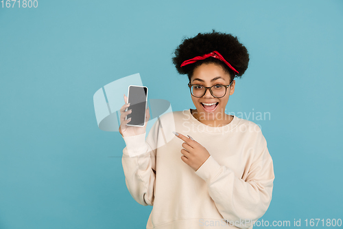 Image of African-american woman\'s portrait isolated on blue studio background with copyspace