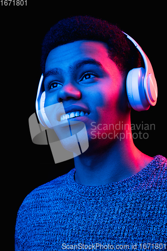 Image of African-american man\'s portrait isolated on black studio background in multicolored neon light