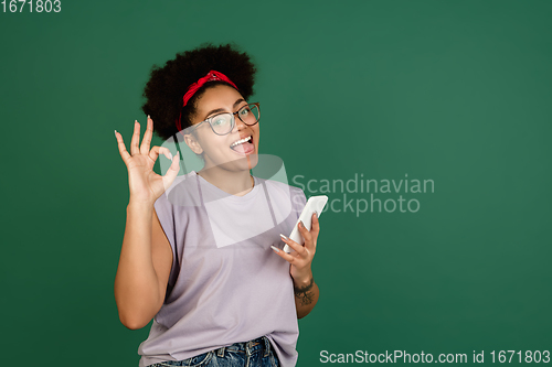 Image of African-american woman\'s portrait isolated on green studio background with copyspace