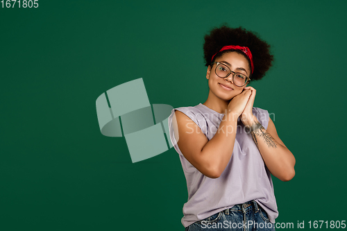 Image of African-american woman\'s portrait isolated on green studio background with copyspace