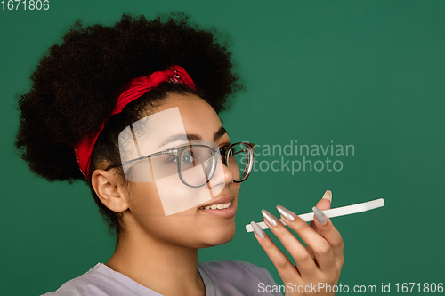 Image of African-american woman\'s portrait isolated on green studio background with copyspace