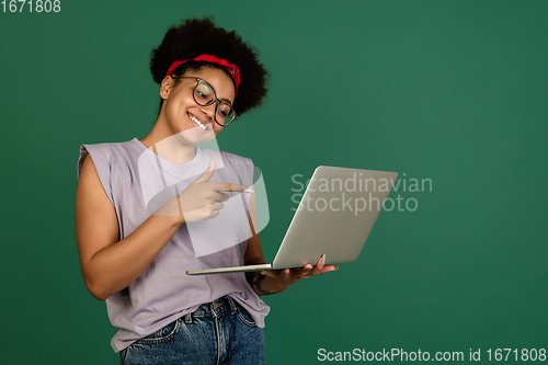 Image of African-american woman\'s portrait isolated on green studio background with copyspace