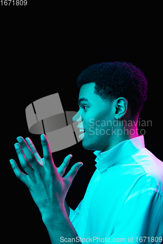 Image of African-american man\'s portrait isolated on black studio background in multicolored neon light