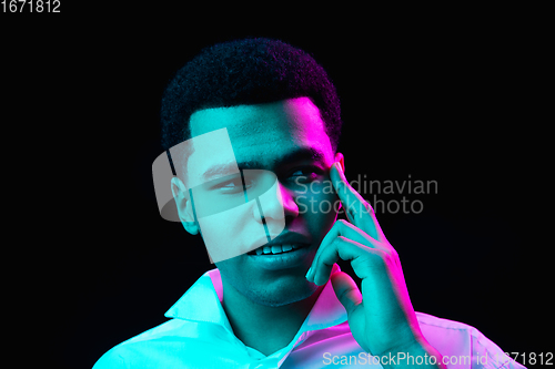 Image of African-american man\'s portrait isolated on black studio background in multicolored neon light