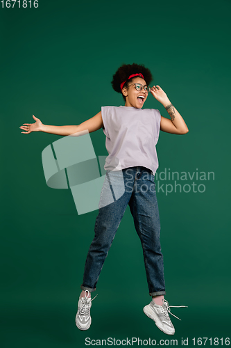 Image of African-american woman\'s portrait isolated on green studio background with copyspace