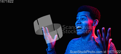 Image of African-american man\'s portrait isolated on black studio background in multicolored neon light