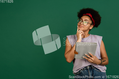 Image of African-american woman\'s portrait isolated on green studio background with copyspace