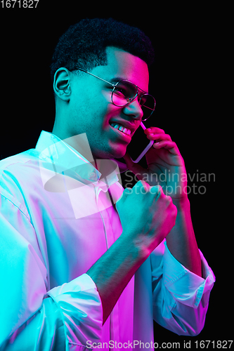 Image of African-american man\'s portrait isolated on black studio background in multicolored neon light