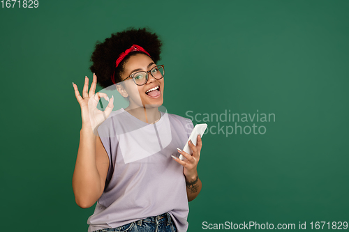 Image of African-american woman\'s portrait isolated on green studio background with copyspace