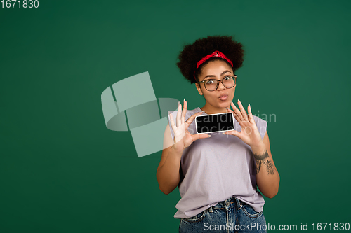 Image of African-american woman\'s portrait isolated on green studio background with copyspace