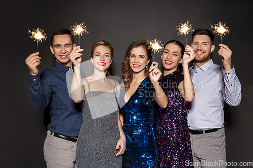 Image of happy friends in party clothes with sparklers