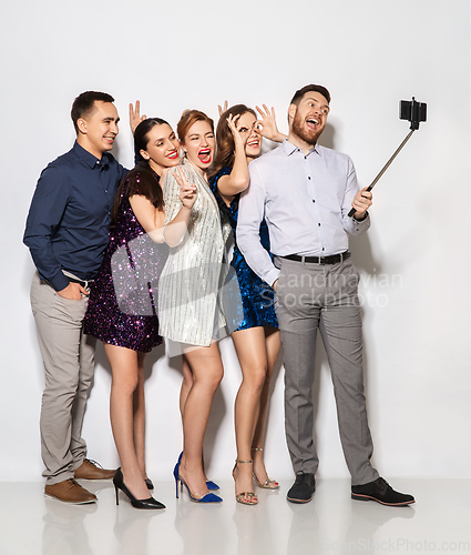 Image of happy friends taking selfie by smartphone at party