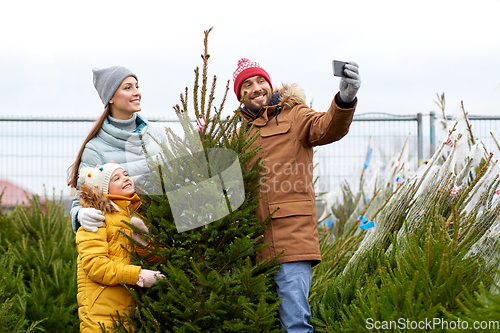 Image of family taking selfie with christmas tree at market