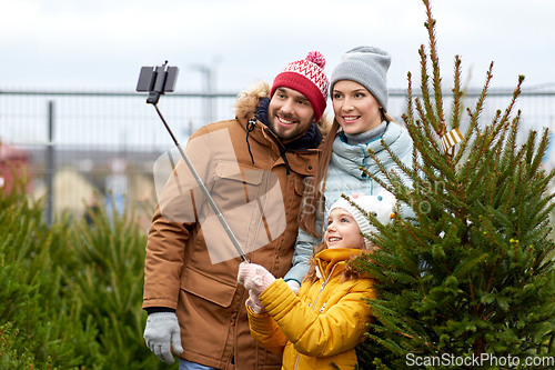 Image of family taking selfie with christmas tree at market