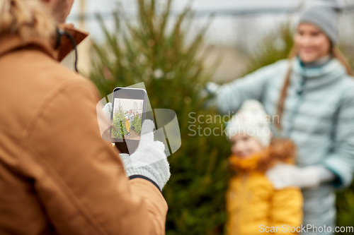 Image of family taking picture of christmas tree at market