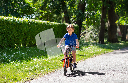 Image of happy little boy riding bicycle at summer park