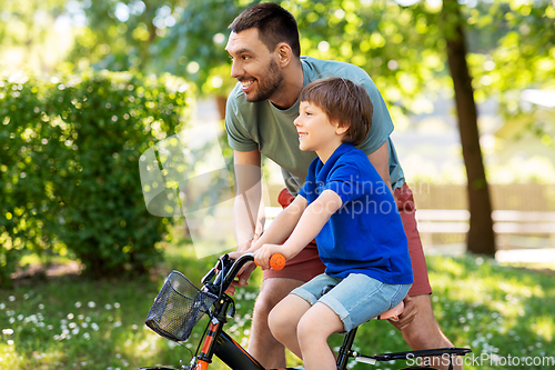 Image of father teaching little son to ride bicycle at park