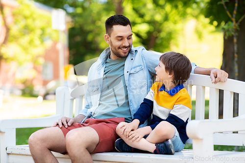 Image of father with son sitting on park bench and talking