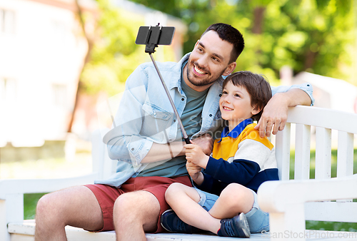 Image of father and son taking selfie with phone at park