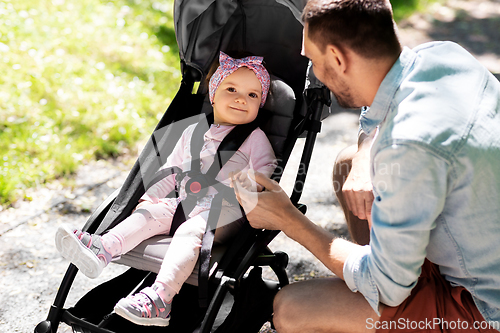 Image of happy father with child in stroller at summer park