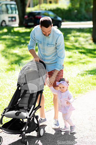 Image of father with child and stroller walking at park