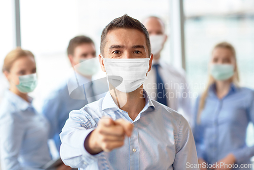 Image of businessman in mask pointing finger at office