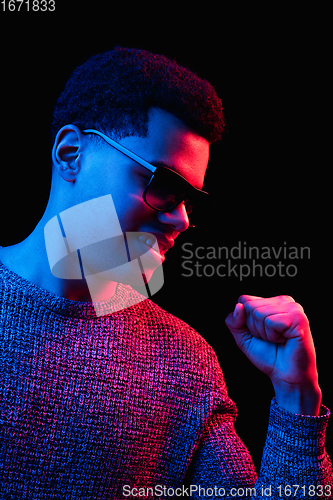 Image of African-american man\'s portrait isolated on black studio background in multicolored neon light