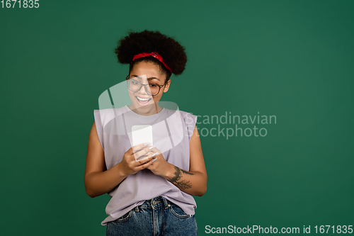 Image of African-american woman\'s portrait isolated on green studio background with copyspace