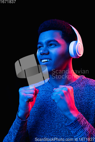 Image of African-american man\'s portrait isolated on black studio background in multicolored neon light
